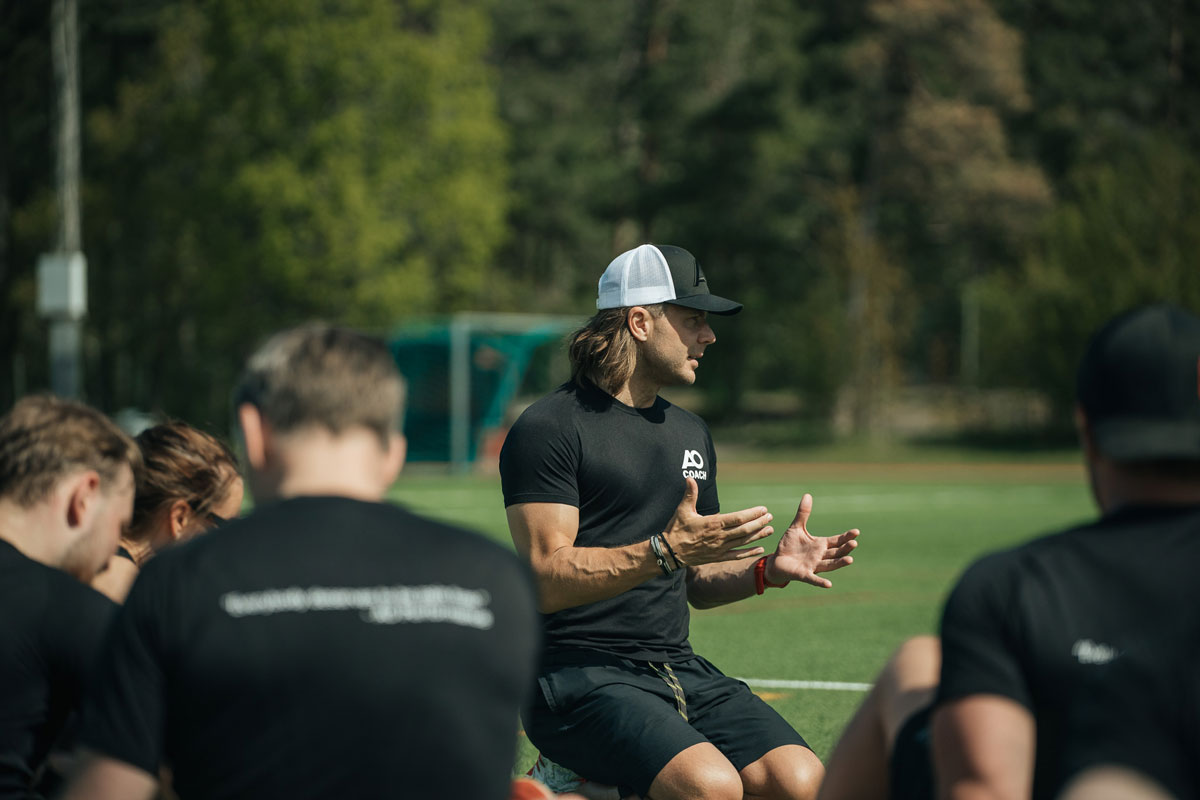 Tränaren föreläser kunder på en fotbollsplan.
